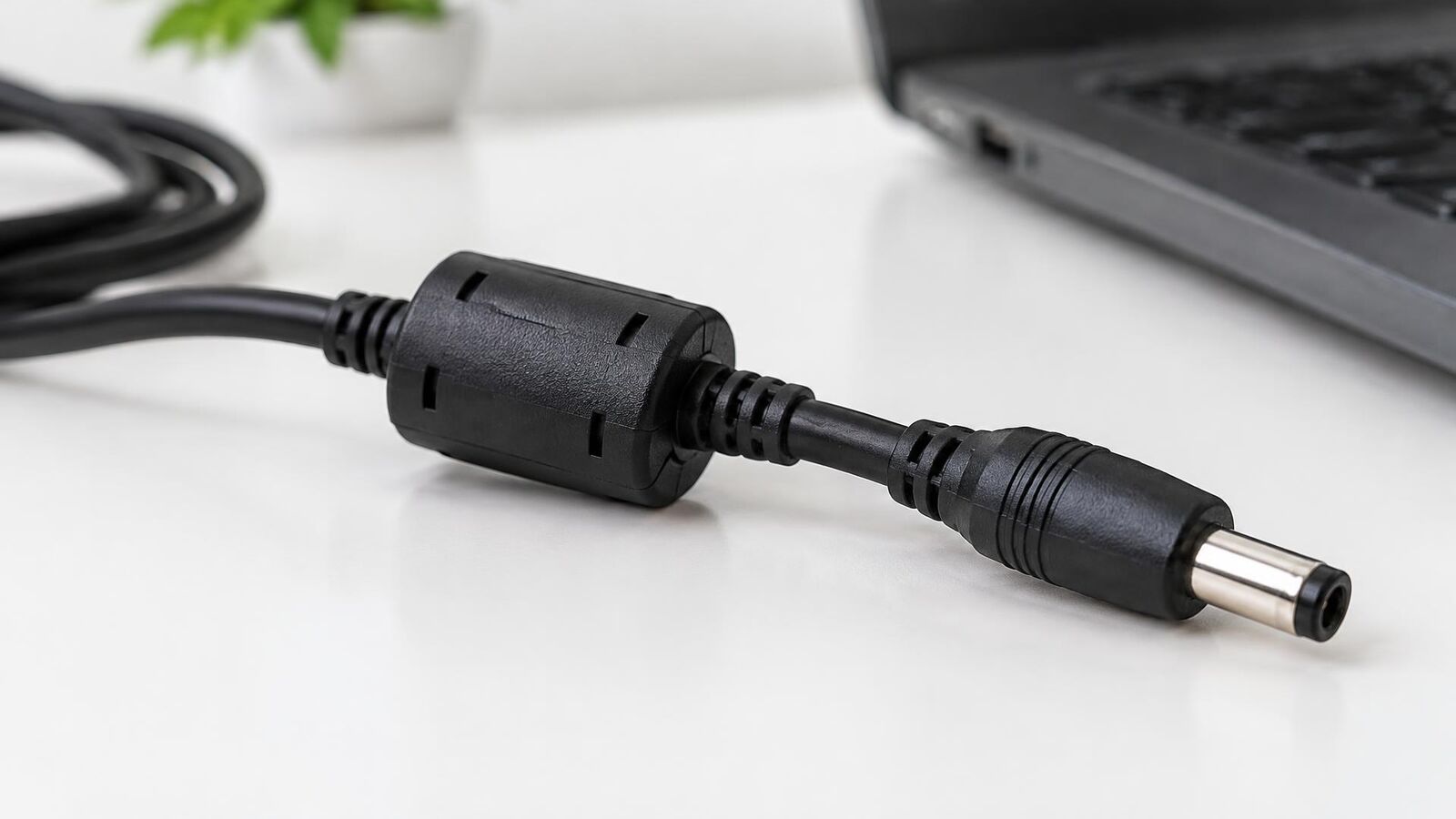 Cabo preto de carregador de notebook com o cilindro de ferrite perto do conector